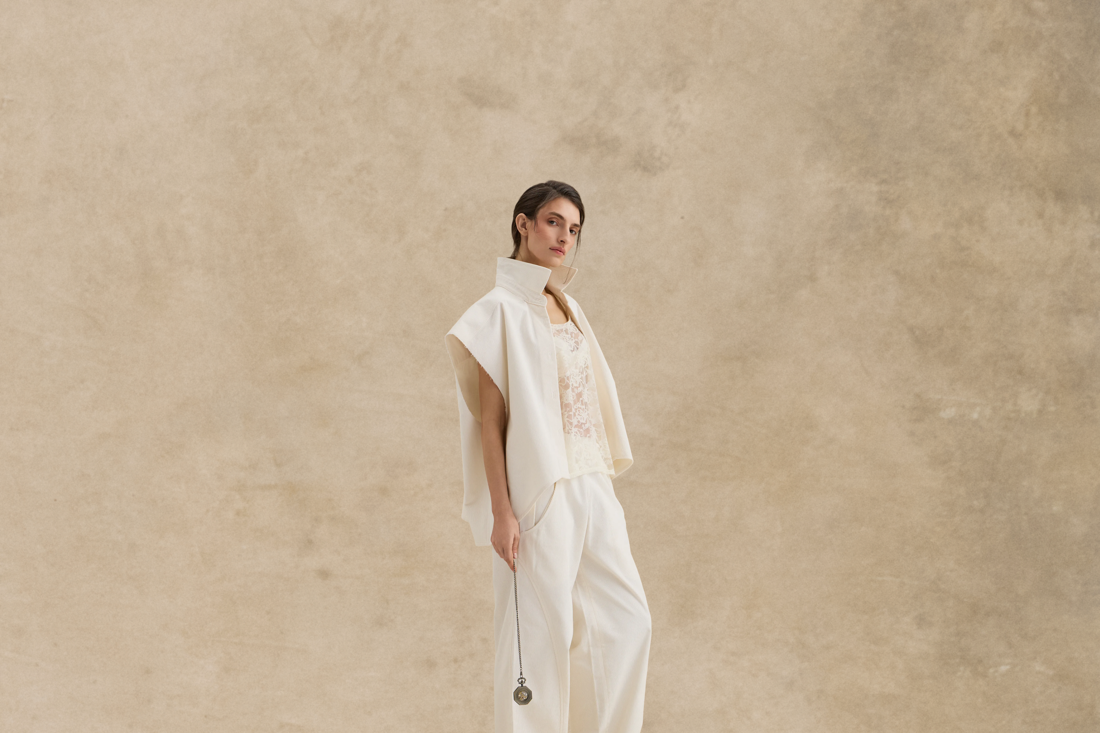 Woman in a white outfit standing against a beige background